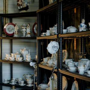 A collection of vintage porcelain and ceramic tableware on shelves, showcasing delicate craftsmanship.