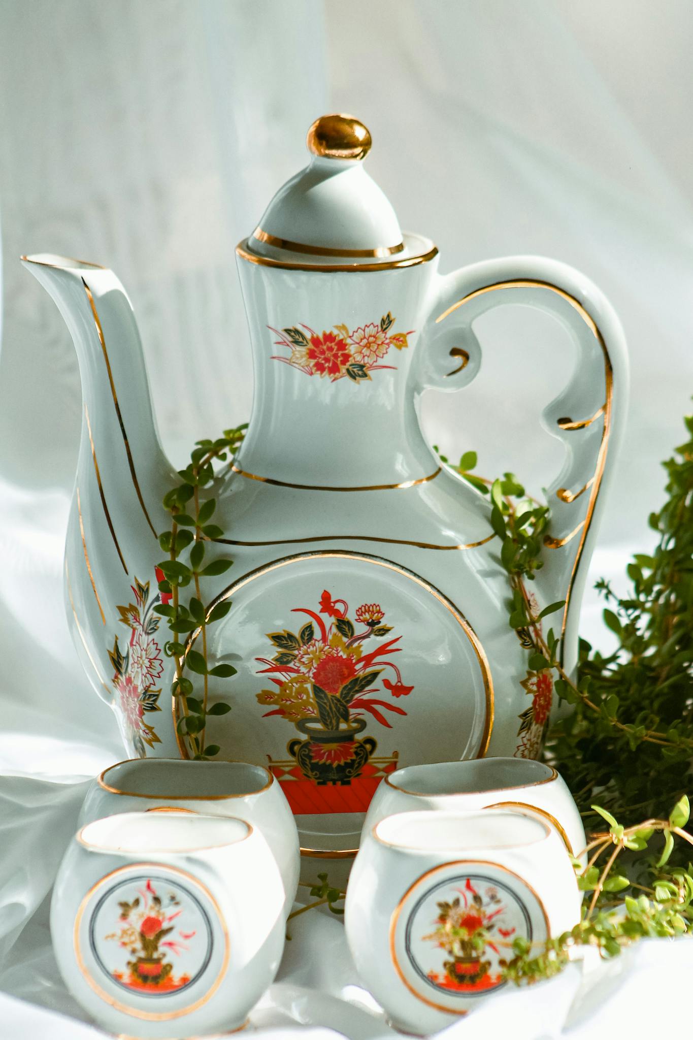 Ornate traditional porcelain teapot and cups with floral design, perfect for classic decor.