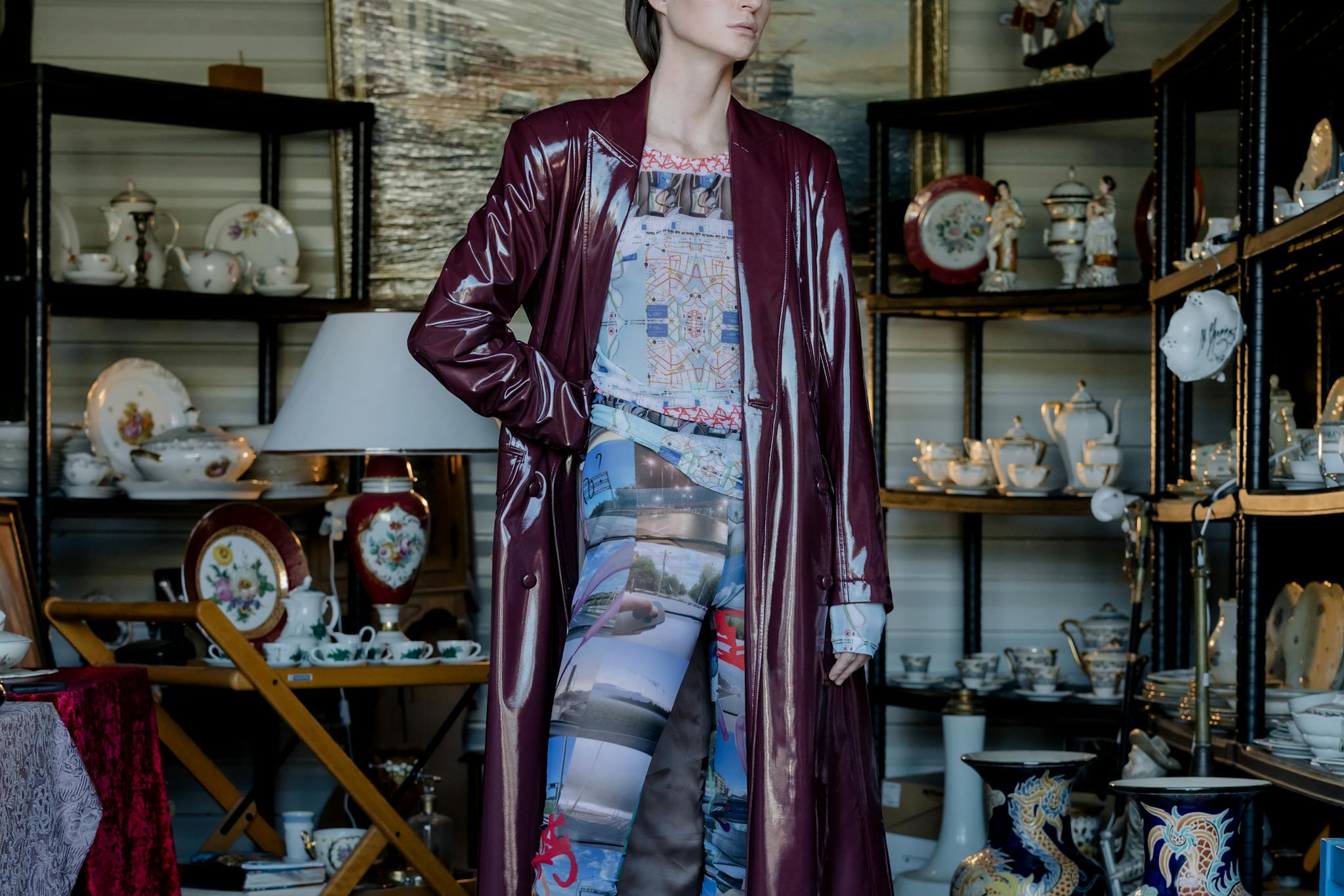 Stylish woman posing among vintage ceramic tableware in an indoor flea market setting.